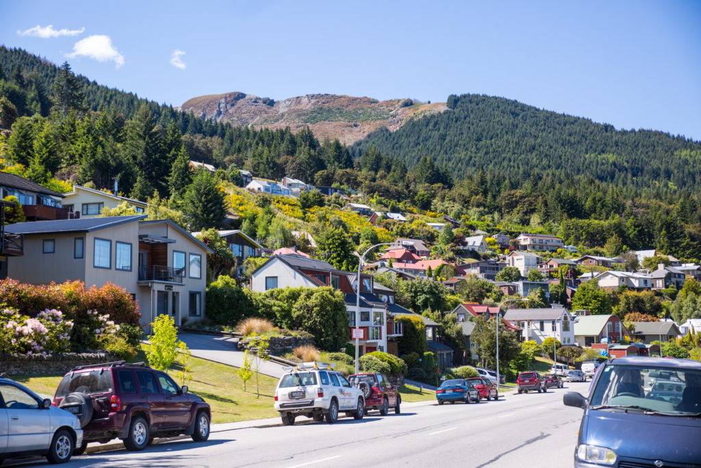 Vibrant suburban street in Queenstown, New Zealand, nestled against lush mountains.